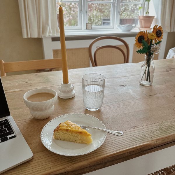 bord med kage computer kaffe og blomster